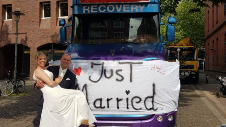Die frisch Vermählten mit einem „Just Married“-Schild an einem Firmen-Lkw.