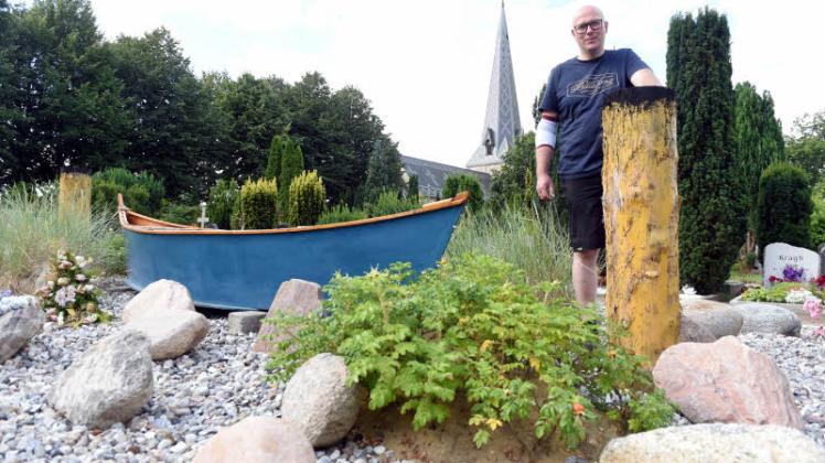 Friedhofsverwalter Kai Brix an dem Bestattungsfeld mit Boot und Pollern.
