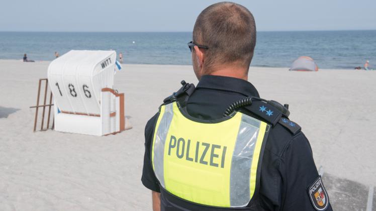 Ein Polizist beim Streifengang vor der Seebrücke am Strand von Graal-Müritz. In Mecklenburg-Vorpommern sind wegen des Einreiseverbots für Tagestouristen zahlreiche Anzeigen aufgenommen worden.