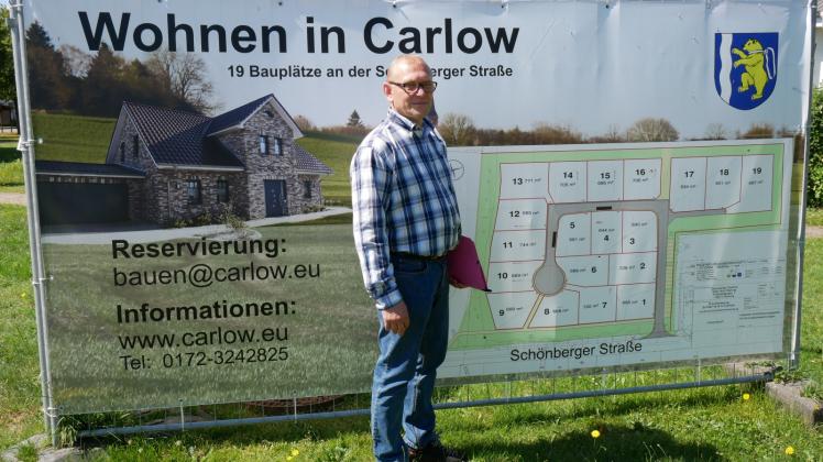 An der Turnhalle in Carlow steht eins der fünf Plakate, wie Bürgermeister Reinhard Wienecke zeigt. 