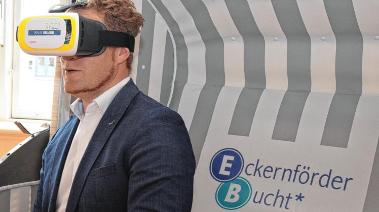 Der Geschäftsführer der Eckernförde Touristik & Marketing GmbH, Stefan Borgmann, mit einer VR-Maske, die ihm die virtuelle 360-Grad-Ansicht eines Eckernförder Luftbildes zeigt.