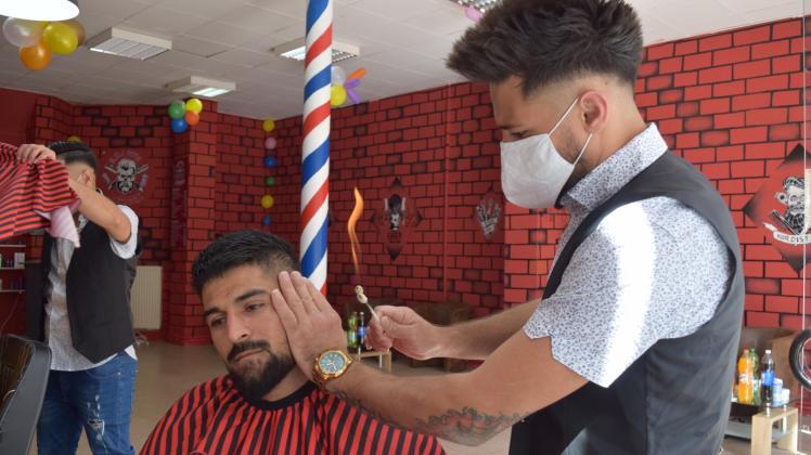 Schero Mohamad demonstriert die Haarentfernung am Ohr mithilfe der Flamme 