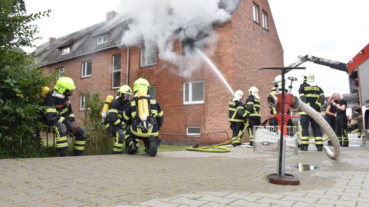Für die Feuerwehrleute unter Atemschutz (l.) hieß es zunächst einmal warten, bis die Kameraden den Brand eines Mehrfamilienhauses in Boizenburg von außen bekämpft hatten. 
