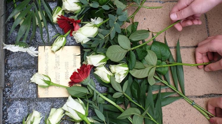 Schüler aus Dettmannsdorf legen Blumen auf dem Denkstein für den Rostocker Gustav Max Posner nieder.