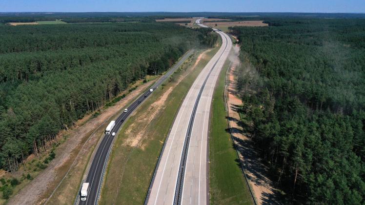 Ein neues Teilstück der Autobahn 14 ist vor der Eröffnung des Teilstücks zu sehen, während auf der Bundesstraße 189 (links) Fahrzeuge fahren.