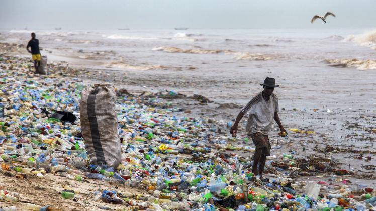 Ein Mann sammelt verwertbaren Plastikmüll am verschmutzten Korle Gonno Strand in Ghana.