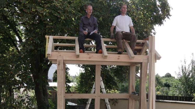Lehmbauer Martin Dörfel (l.) verliest mit Zimmermann Martin Schmidt auf den Dachbalken sitzend den speziellen Richtspruch für die Handwerkshütte. 