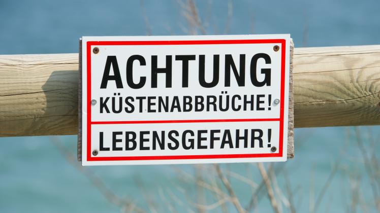 Blick auf ein Warnschild, das auf die Abbruchgefahr an der Steilküste auf der Insel Rügen hinweist