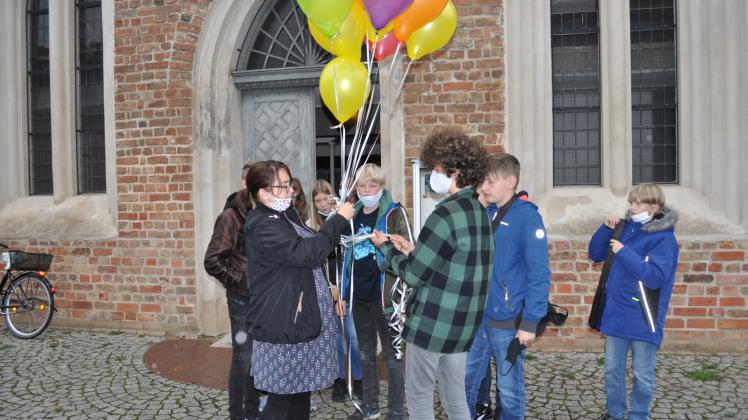 Zusammen mit der Gemeindepädagogin Mareen Voss lassen die Konfirmanden die Ballons fliegen.