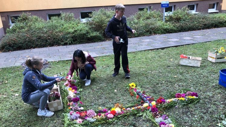 Schüler der 6. Klasse legen eine große 40 aus Blumen, Blättern, Kastanien und allerlei anderen Dingen, die der Herbst zu bieten hat. 