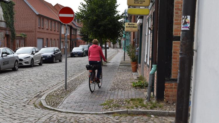 Bei diesem gestellten Bild macht die Frau auf dem Fahrrad einiges verkehrt. Ein Helm ist empfohlen, jedoch nicht vorgeschrieben. Aber sie passiert die Baustraße auf dem Gehweg entgegengesetzt der zugelassenen Fahrtrichtung. 