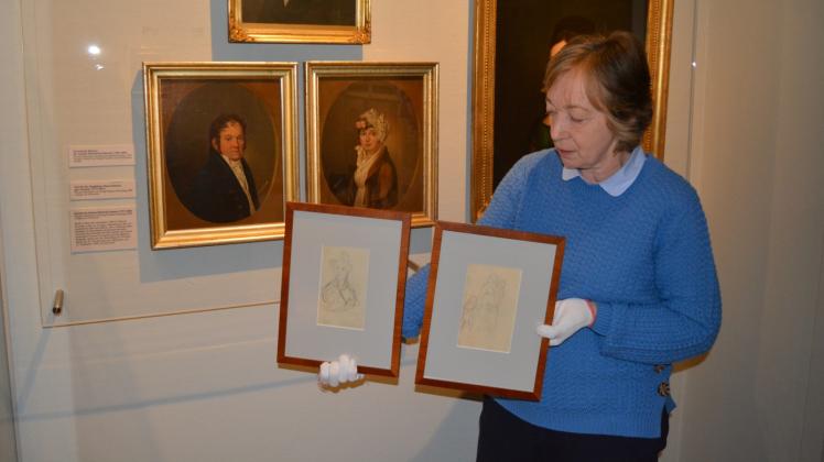 Eine der beiden Zeichnungen des Malers Kersting , die Iris Brüdgam hier präsentiert, wurde dem Stadtmuseum jetzt geschenkt. Die andere kann weitere zehn Jahre im Museum verbleiben. Die beiden Porträts im Hintergrund sollen nun erworben werden.