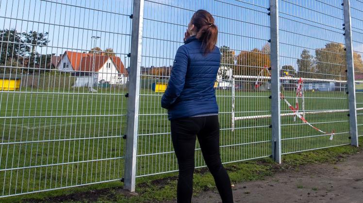 Eine Frau steht vor einem Lärmschutzzaun an einer Seite des Sportplatzes des Neumühler Sportvereins. Der Bund der Steuerzahler veröffentlichte den Zaun als Beispiel für die Verschwendung von Steuergeldern in seinem Schwarzbuch 2020/21.