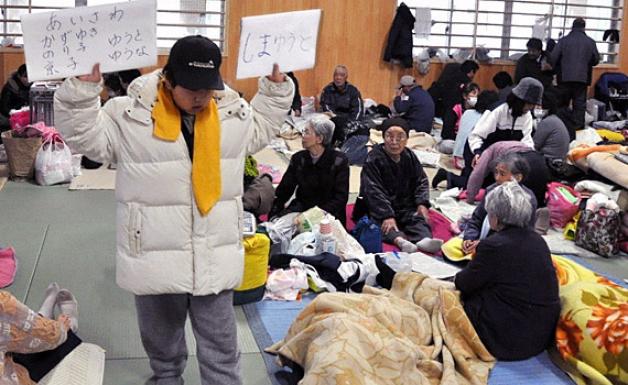 Ein Mann sucht am Freitag, 18. März, in einer Notunterkunft nach Angehörigen. Foto: dpa