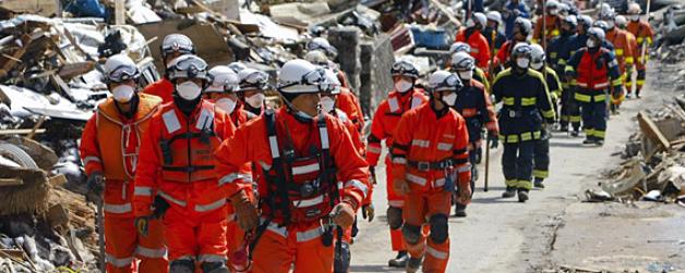 Ein Rettungstrupp aus Feuerwehrleuten läuft zwischen Trümmern der Stadt Kamaishi im Nordosten Japans. Foto: dpa