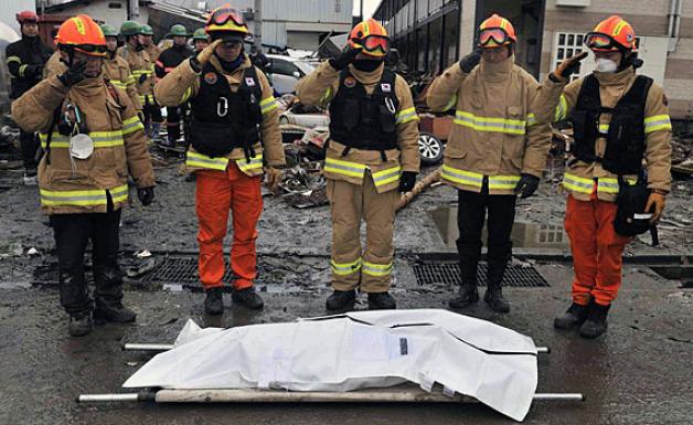Schweigeminute für die Opfer in Japan am Freitag: Helfer aus Südkorea erweisen einem Toten ihren Respekt. Foto: dpa