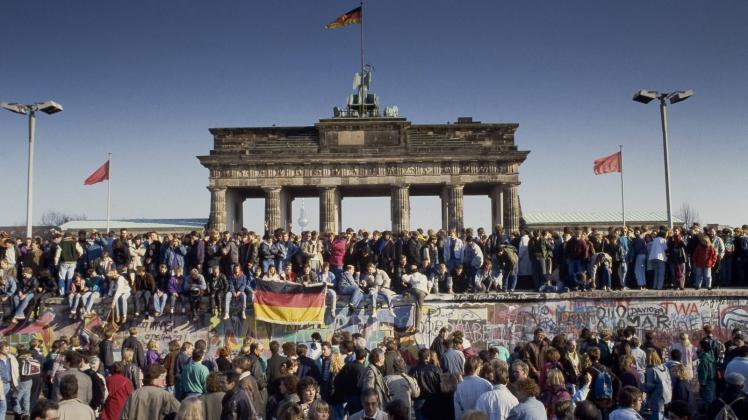 Menschen aus Ost und West feiern den Fall der Berliner Mauer am Brandenburger Tor in Berlin