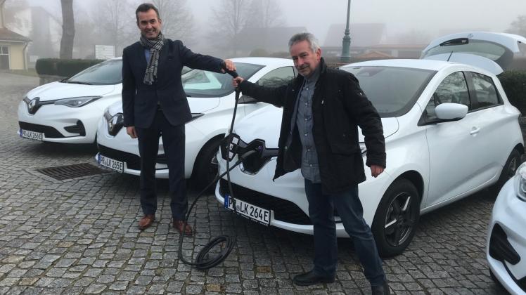 Mitarbeiter Karsten Wachholz erklärt Landrat Torsten Uhe die neuen E-Autos.