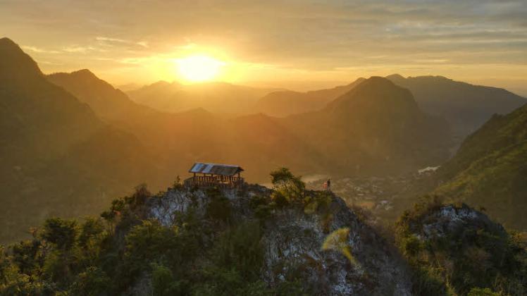 Ein Lieblingsort in Laos: Christopher Fritze (im Vordergrund neben der roten Fahne) blickt über das Tal auf den Berg „Nong Khiaw“. 