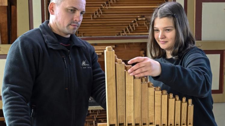 Thomas Lang, Orgelbaumeister von der Firma Orgelbau Sauer und Meta März, Auszubildende zur Orgelbauerin, stehen neben einer kleinen mechanische Baukastenorgel. 