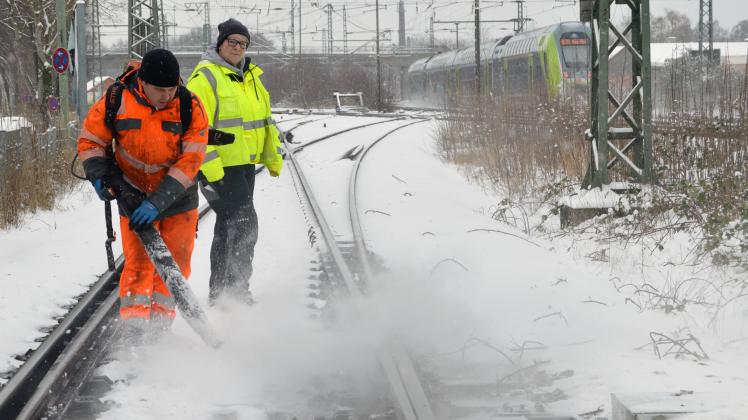 Im Bereich des Elmshorner Bahnhofs kümmert sich ein Winterdiensttrupp der Deutsche Bahn darum, eine Weich von Eis zu befreien.