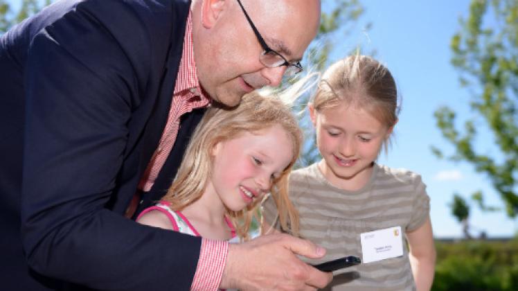 Bildung ist eines der Hauptthemen. Torsten Albig zeigt auf dem Bürgerkongress Kindern Fotos auf einem Smartphone. Foto: dpa