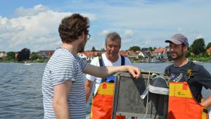 Umweltminister Jan Philipp Albrecht (v.l.) fährt mit Fischer Jörn Ross und dessen Sohn Nils zum Fischfang auf die Schlei hinaus.