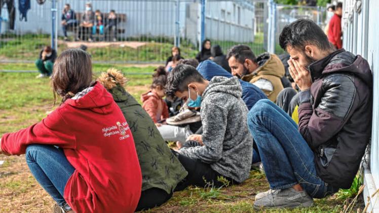 Migranten sitzen vor Containern in der Zentralen Erstaufnahmeeinrichtung für Asylbewerber (ZABH) des Landes Brandenburg in Eisenhüttenstadt.