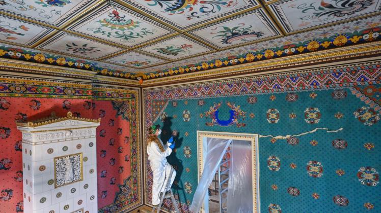 Restauratorin Dorothee Schmidt-Breitung arbeitet an der grünen Papiertapete des Türkischen Zimmers im Schloss Branitz. Patrick Pleul/dpa