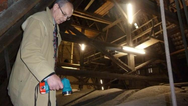Hoch oben  in der Kirchturmspitze: Pastor Stefan Henrich inspiziert mit einem Handstrahler die Schäden im Gewölbe. 