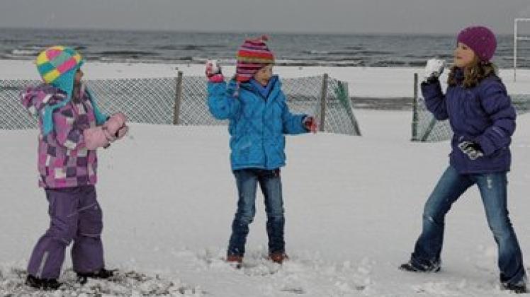 Schneeballschlacht: Emily, Annelie und Annouk  amüsieren sich prächtig am Strand.