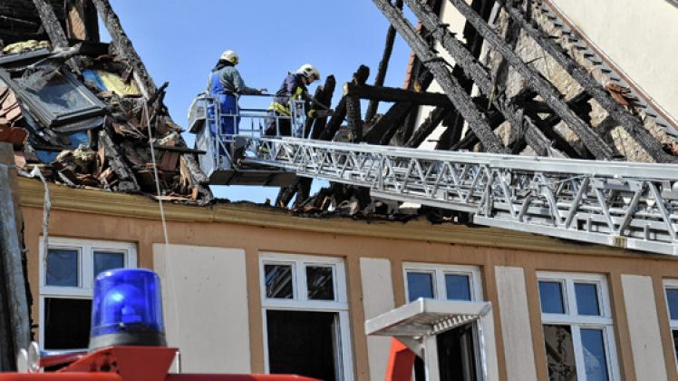 Kameraden der Wittenberger Feuerwehr tragen als Schutzmaßnahme den Schornstein des abgebrannten Hauses ab.  Lisa kleinpeter