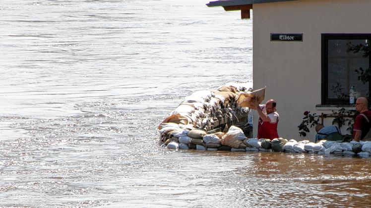 Nur noch Zentimeter: Ein Mann sichert am Elbtor in Schönebeck sein Haus mit Sandsäcken. Foto: Peter Förster