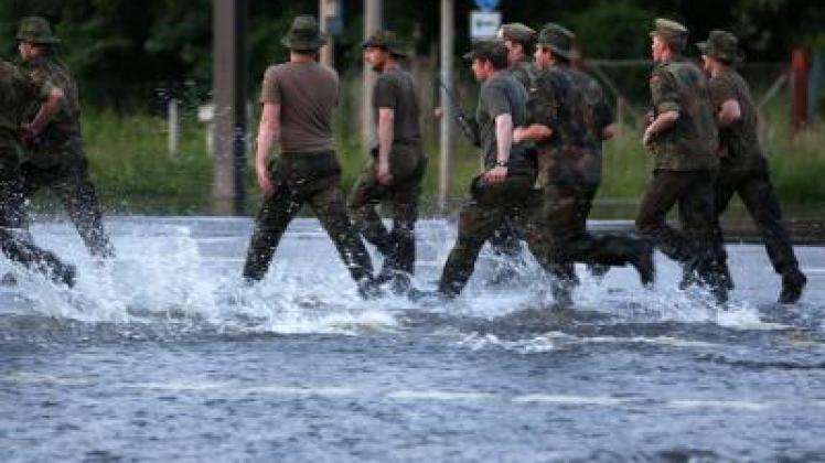  Bundeswehrsoldaten rennen im Ortsteil Rothensee in Magdeburg über eine überflutete Straße. Foto: Jens Büttner 