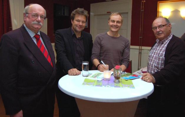 Im Beisein von Groß Vollstedts Bürgermeister Heinz Volkmann (li.) und Umweltminister Robert Habeck (2. v. li.) signierte Kim Schmidt eines seiner Bücher für Dagobert Holona (re.), der extra für die Ausstellungseröffnung aus Tarp angereist war. Im Beisein von Groß Vollstedts Bürgermeister Heinz Volkmann (li.) und Umweltminister Robert Habeck (2. v. li.) signierte Kim Schmidt eines seiner Bücher für Dagobert Holona (re.), der extra für die Ausstellungseröffnung aus Tarp angereist war.