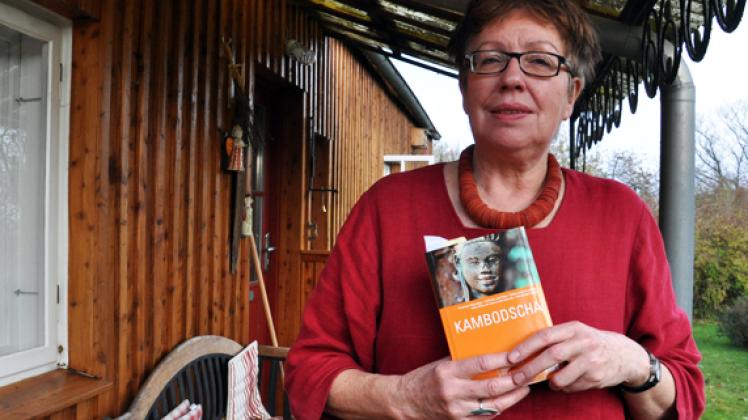 Beate Schneider vor ihrem Haus in Zülow mit einem Reiseführer von Kambodscha. Für ein Jahr wird die 61-Jährige in dem ostasiatischen Land als Au-Pair-Großmutter in einer Familie leben und sich um einen dreijährigen Jungen kümmern. Am  morgigen Freitag geht ihr Flug.  Michael Beitien