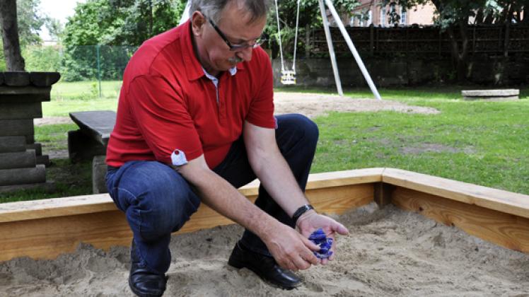 Bürgermeister Norbert Baumann hält ein paar Scherben in der Hand, die im Sandkasten gefunden wurden. hans taken