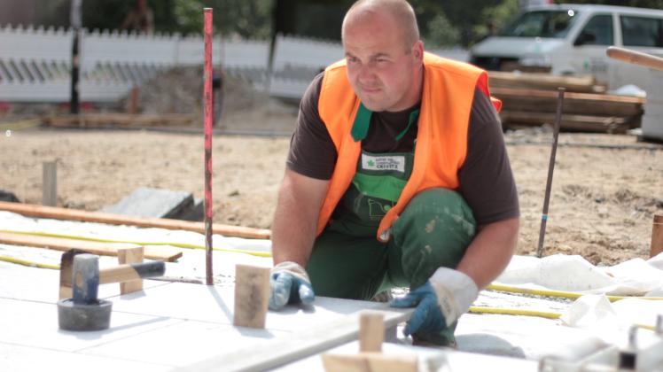 In beinahe filigraner Maßarbeit verlegt Andy Schröder von der Garten- und Landschaftsbau Crivitz GmbH die 100-Kilo-Steine vor dem Kröpeliner Tor. Foto: Dana Bethkenhagen