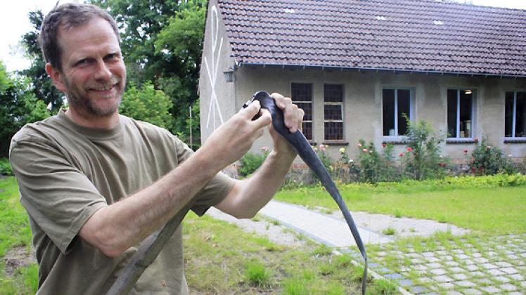 Rainer Finck befestigt das Sensenblatt auf dem Sensenbaum. Er mäht damit des Öfteren Gras. Foto: Nadine Schuldt