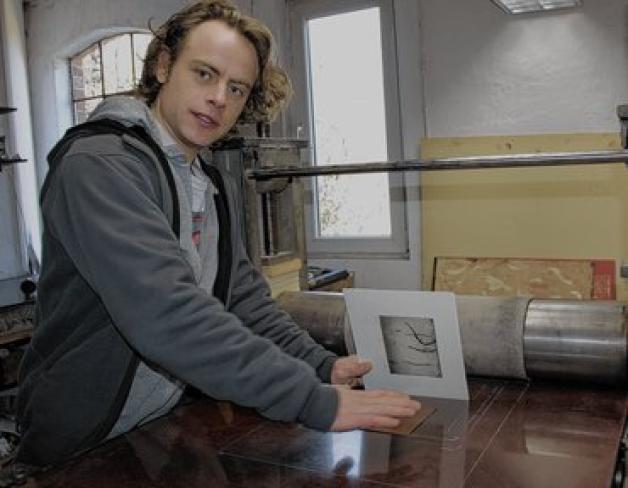 Hannes Schützler veranschaulicht an der Walze, wie die Grafik von der Kupfer-Druckplatte auif das Papier gelangt. Foto: Nadine Schuldt