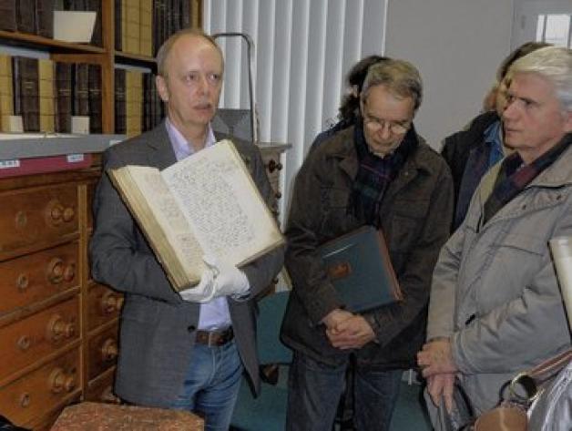 Dr. Karsten Schröder zeigt den Besuchern   des Stadtarchivs ein Stadtbuch von 1515. 