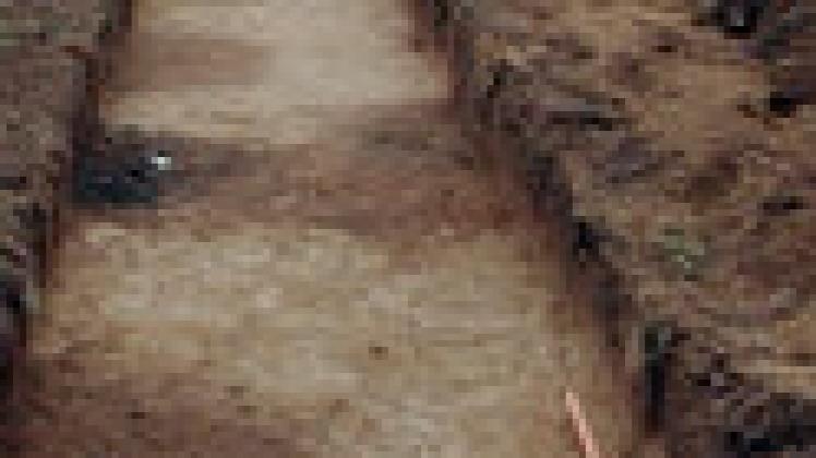 Die dunklen Flecke in diesem archäologischen Schnitt  sind die Gruben, die die letzten Relikte dieser Siedlung repräsentieren. Im Hintergrund sieht man die Gebäude des Wolfshagener Drahtverarbeitung.