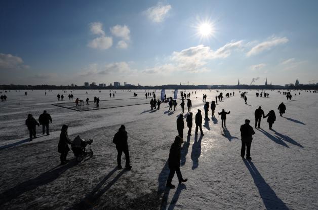 Spaziergänger gehen am Freitag über die zugefrorene Hamburger Außenalster. Foto: Christian Charisius dpa