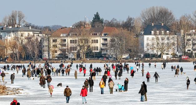 Spaziergänger gehen am Freitag über die zugefrorene Hamburger Außenalster. Foto: Christian Charisius dpa