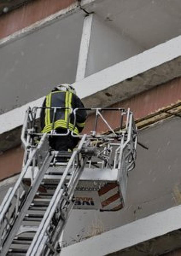 Mit einer Drehleiter steigt ein Feuerwehrmann über den Balkon ein, er will eine Frau retten. Mit einer Drehleiter steigt ein Feuerwehrmann über den Balkon ein, er will eine Frau retten.