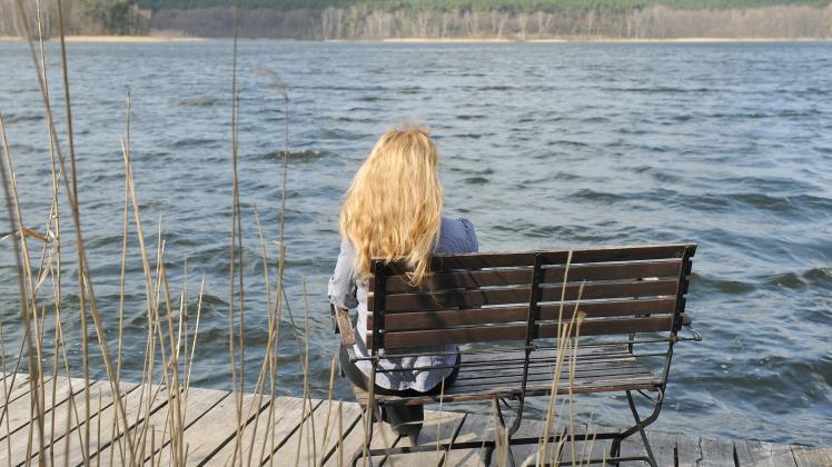 Eine Patientin mit einer Burn-out Erkrankung sitzt auf einer Bank auf einem Steg am großen Glubigsee der Oberbergklinik im brandenburgischen Wendisch Rietz. dpa