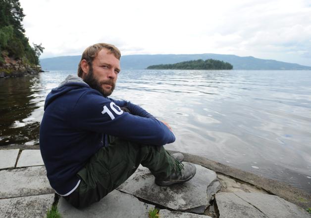 Marcel Gleffe sitzt am Wasser vor der Insel Utoya in Norwegen. Foto: Britta Pedersen dpa