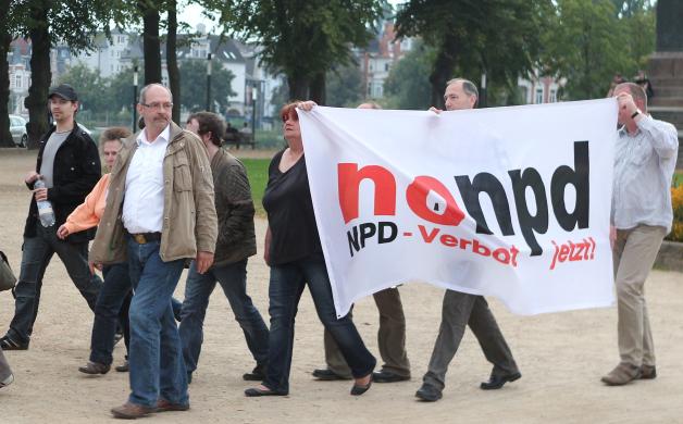 Gegner der NPD gehen in Schwerin nach der Landtagswahl und der Bekanntgabe der ersten Hochrechnungen zu einer Protestaktion mit einem Plakat mit der Aufschrift "nonpd - NPD-Verbot jetzt!" zum Schweriner Schloss. Foto: dpa