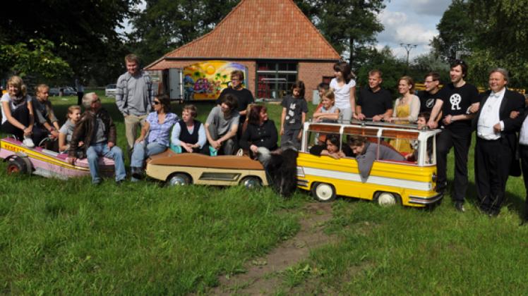 Entspanntes Gruppenbild der Theatercrew, die kleinen Metallautos gehören zum Stück.Pohle 