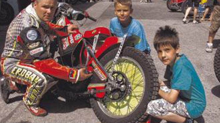 Iven Kammin (r.) und Paul-Martin Schulz ließen sich von Speedway-Fahrer Andreas Neumann erklären, wie die Kette der Rennmaschine gespannt wird.Anne Schwartz